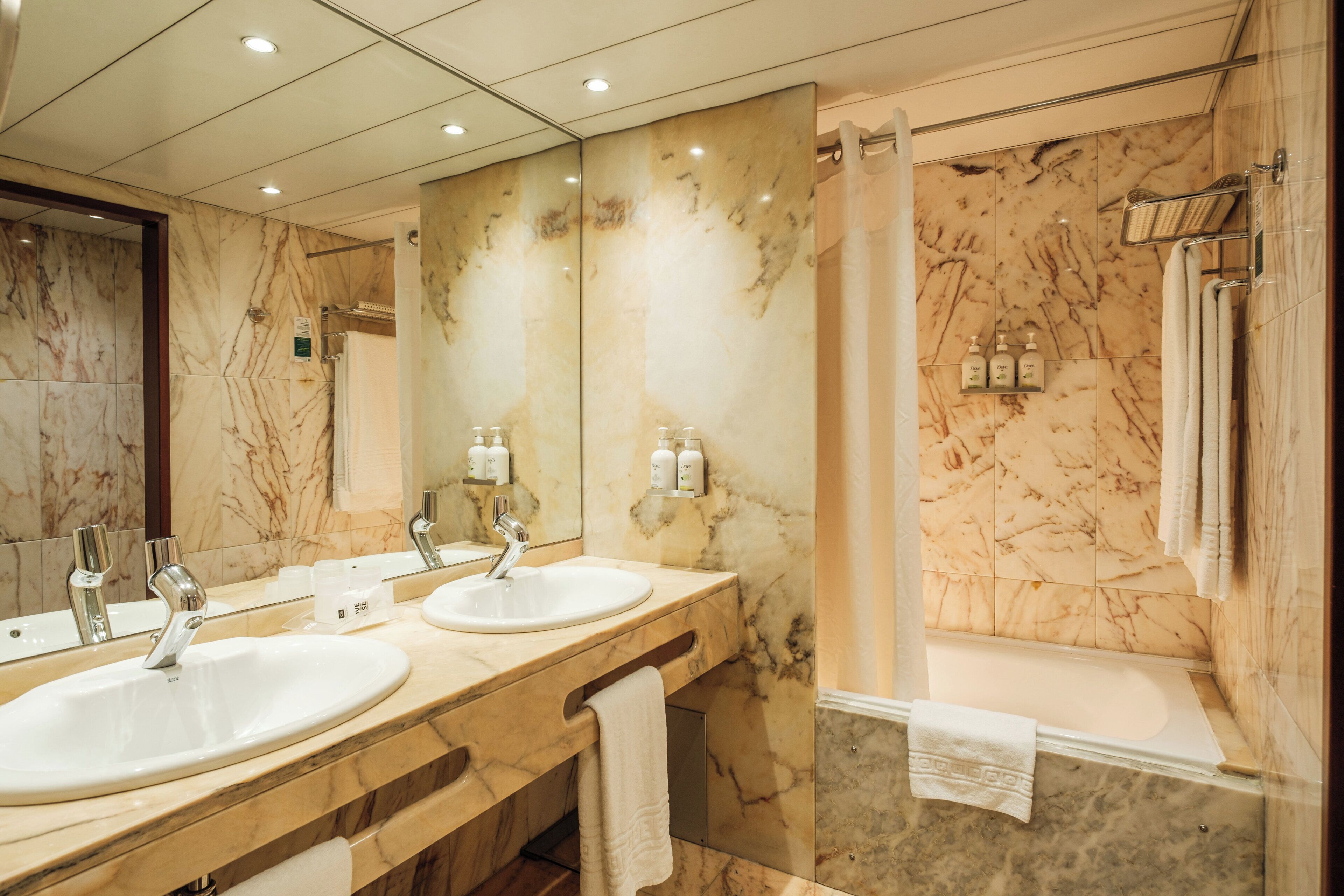 A bathroom with two sinks, a mirror, a shower, and a bathtub.
