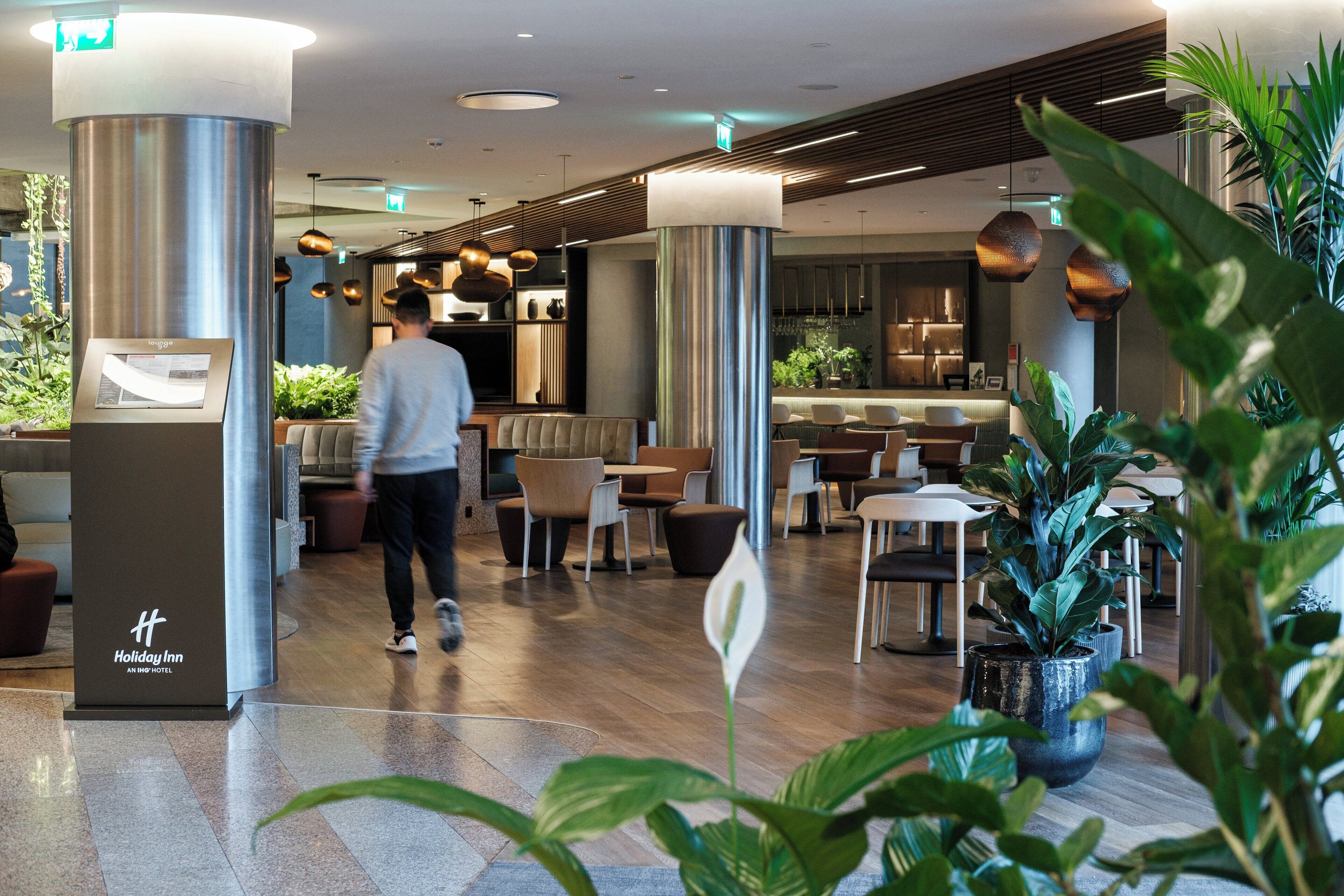 Een moderne hotellobby met een receptiebalie, een zithoek en een bar.