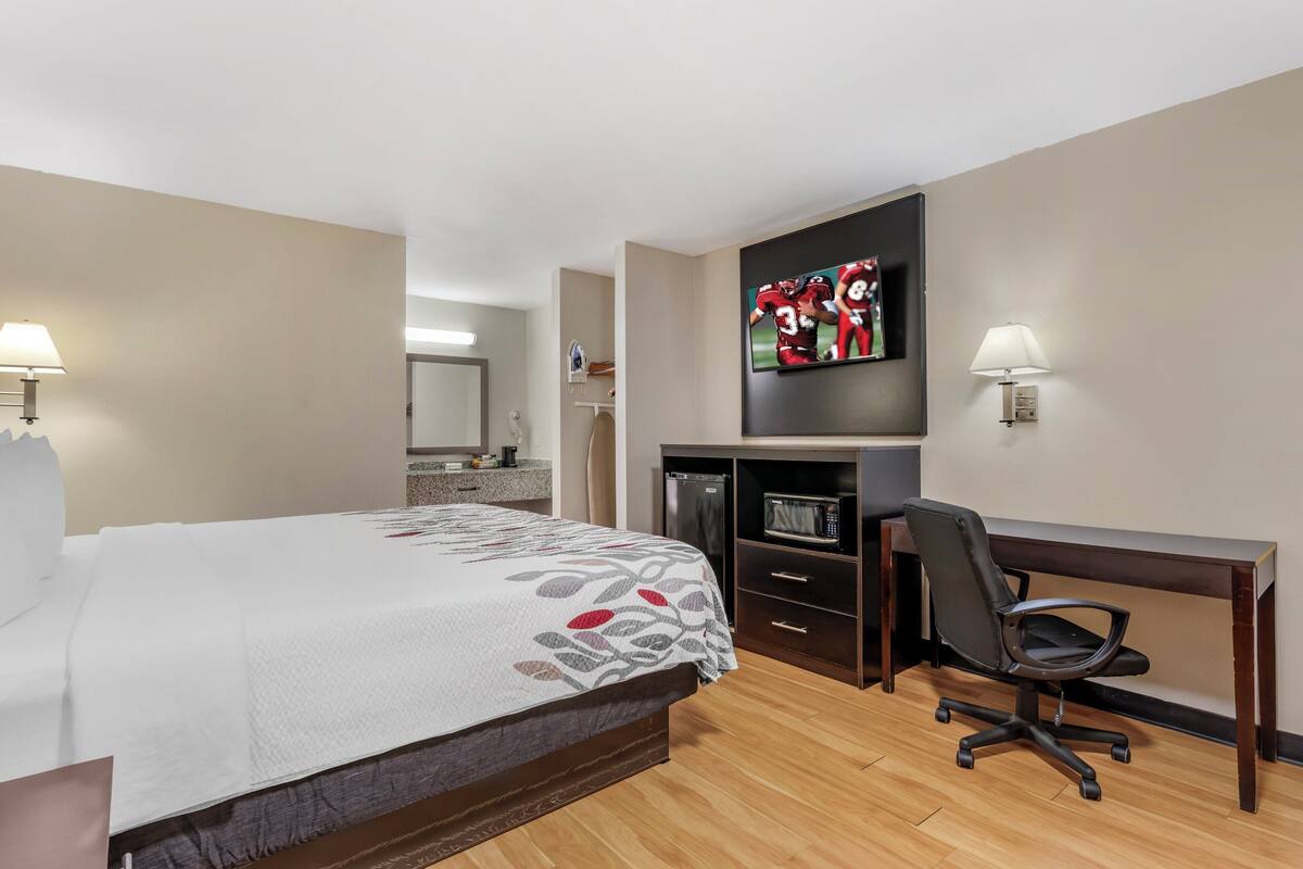Una habitación de hotel con cama, escritorio, televisión y microondas.