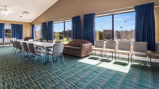 A spacious room with a large table and chairs, a sofa, and a view of the outdoors through large windows. - Red Roof Inn Atlanta - Kennesaw State University (Kennesaw)