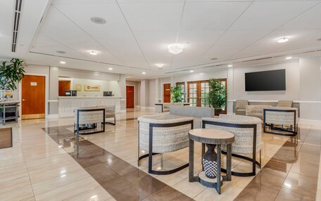A spacious lobby with a reception desk, seating area, and a large flat-screen TV mounted on the wall.