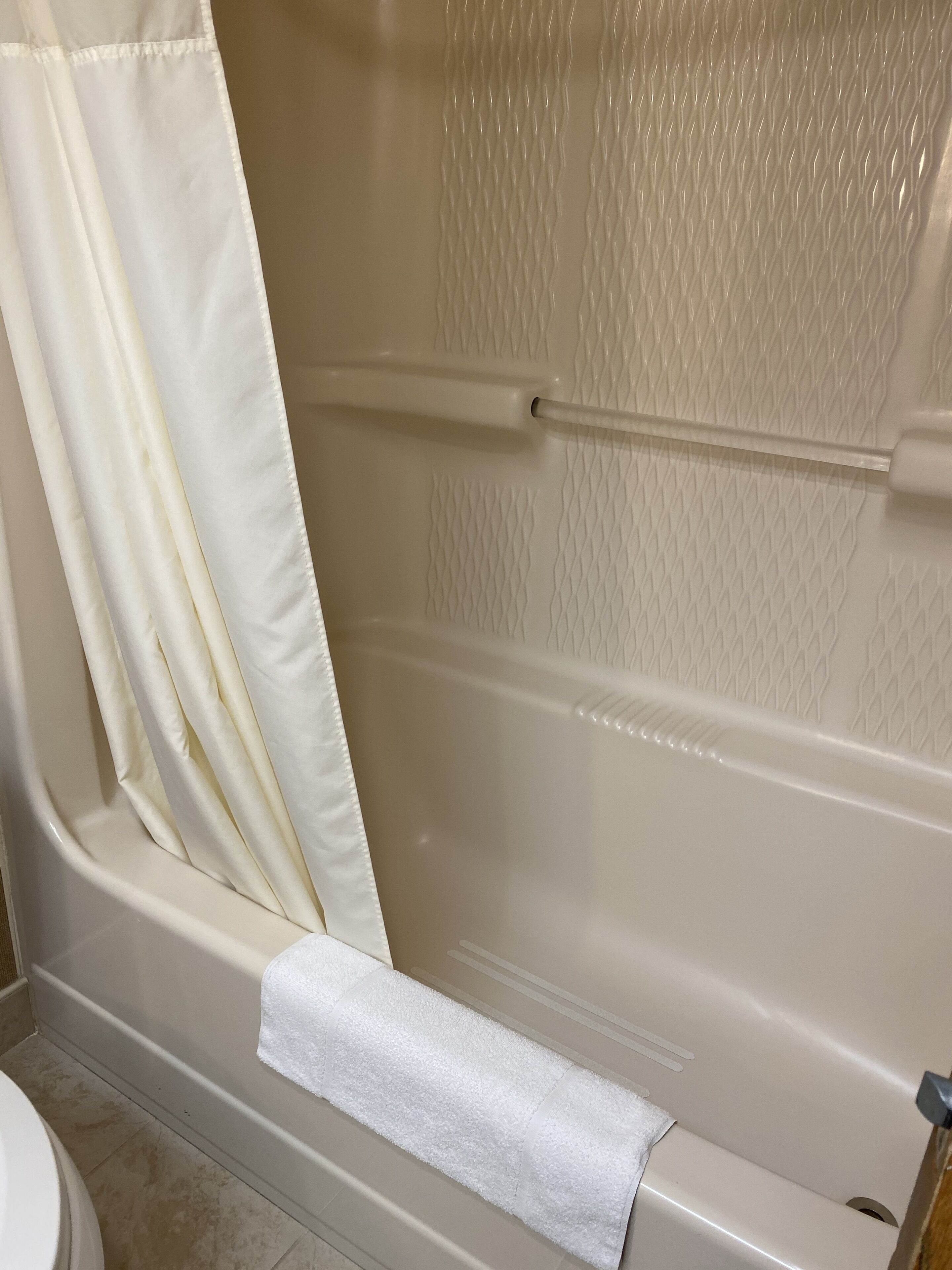 Een badkamer met een bad, een douchegordijn en een handdoekrek.