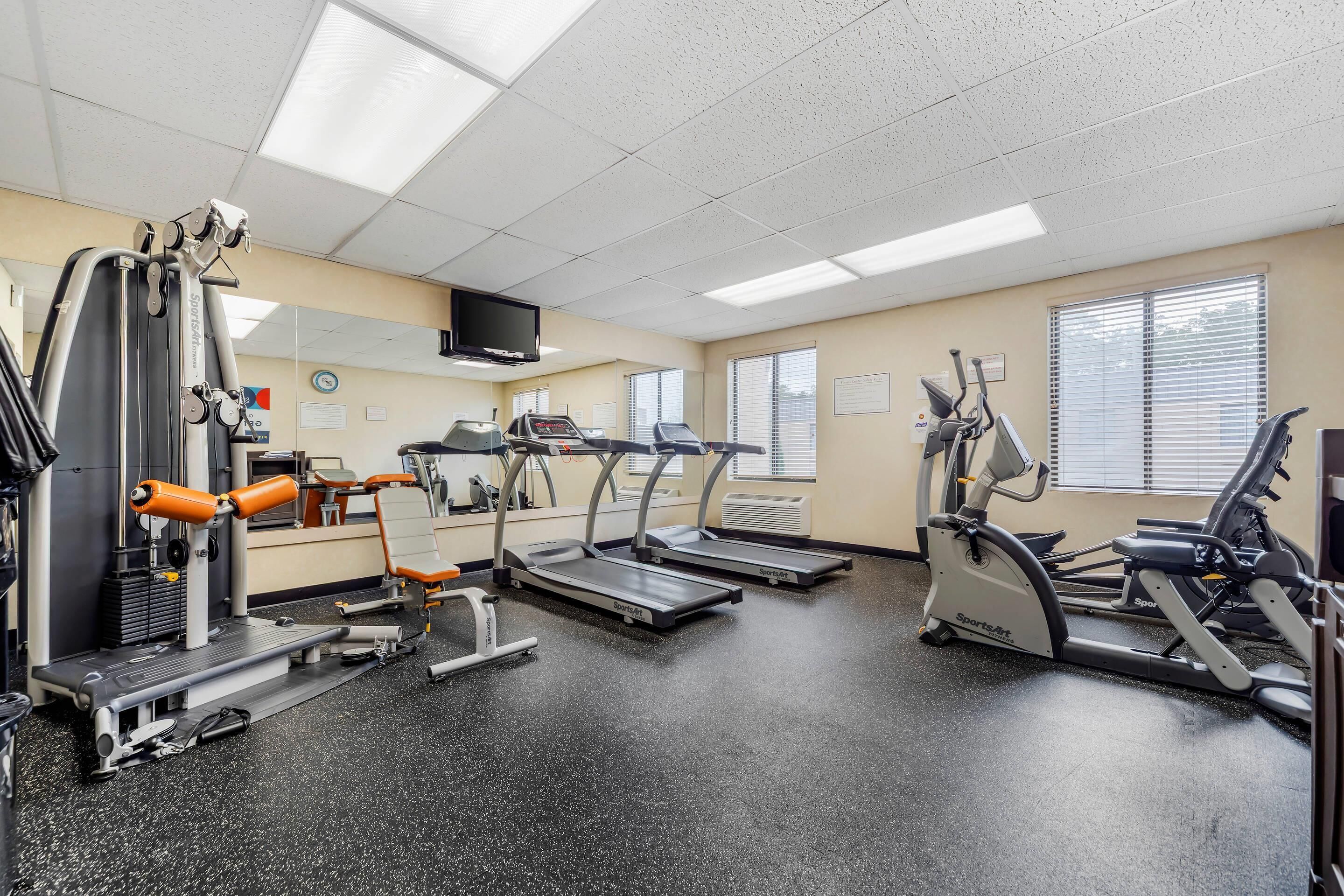 A gym with treadmills, elliptical machines, and weight machines.
