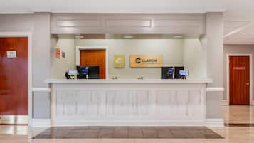 Un mostrador de recepción con el letrero de Clarion by Choice Hotels, dos monitores de computadora y una barra de recepción.