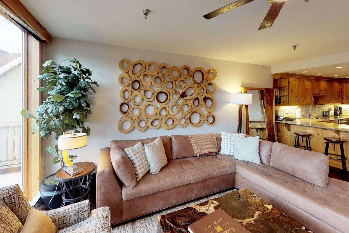A modern living room with a sectional sofa, a coffee table, and a large potted plant.