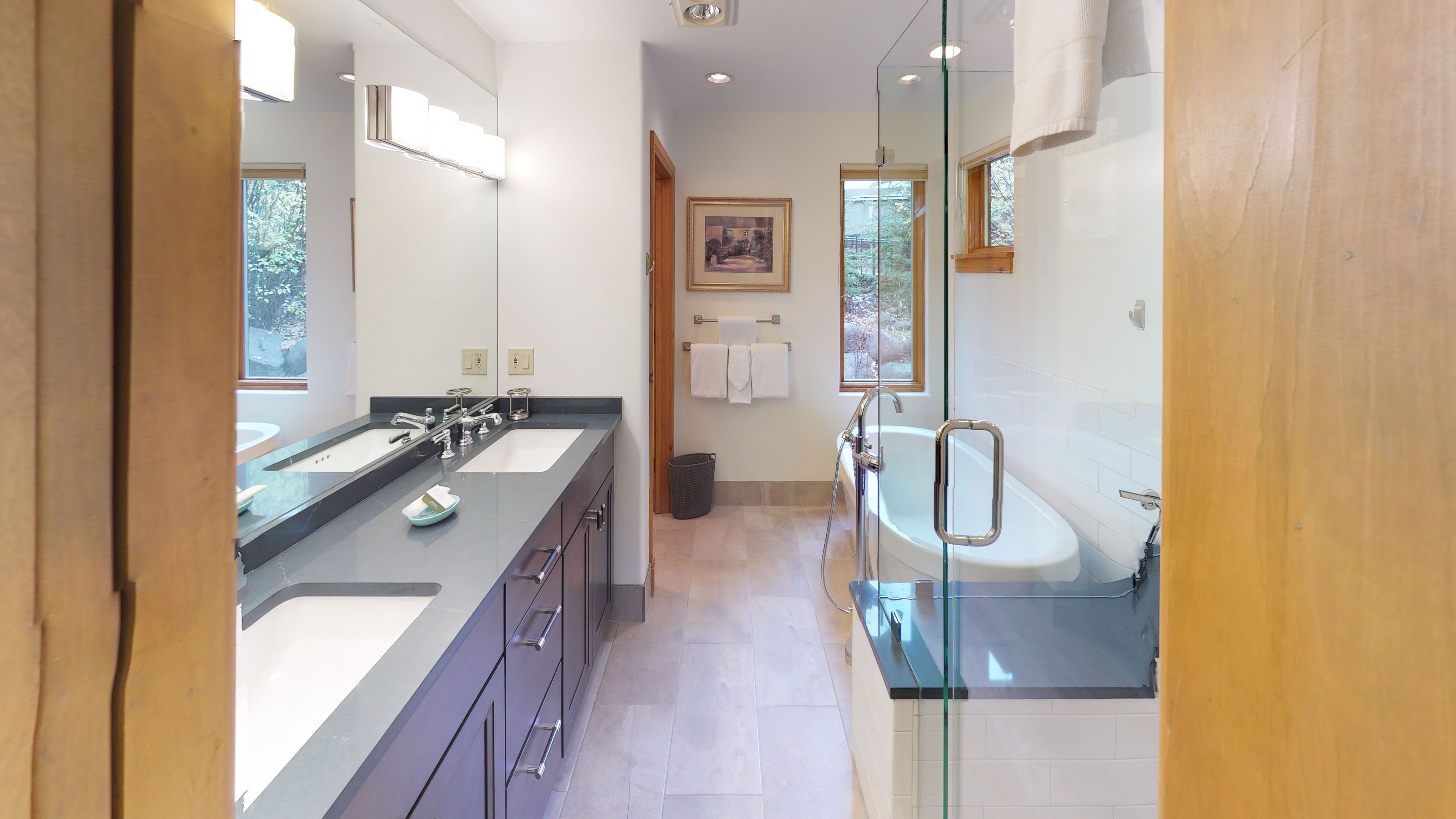A modern bathroom with dual sinks, a glass shower enclosure, and a large mirror.