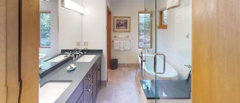 A modern bathroom with dual sinks, a glass shower enclosure, and a large mirror.