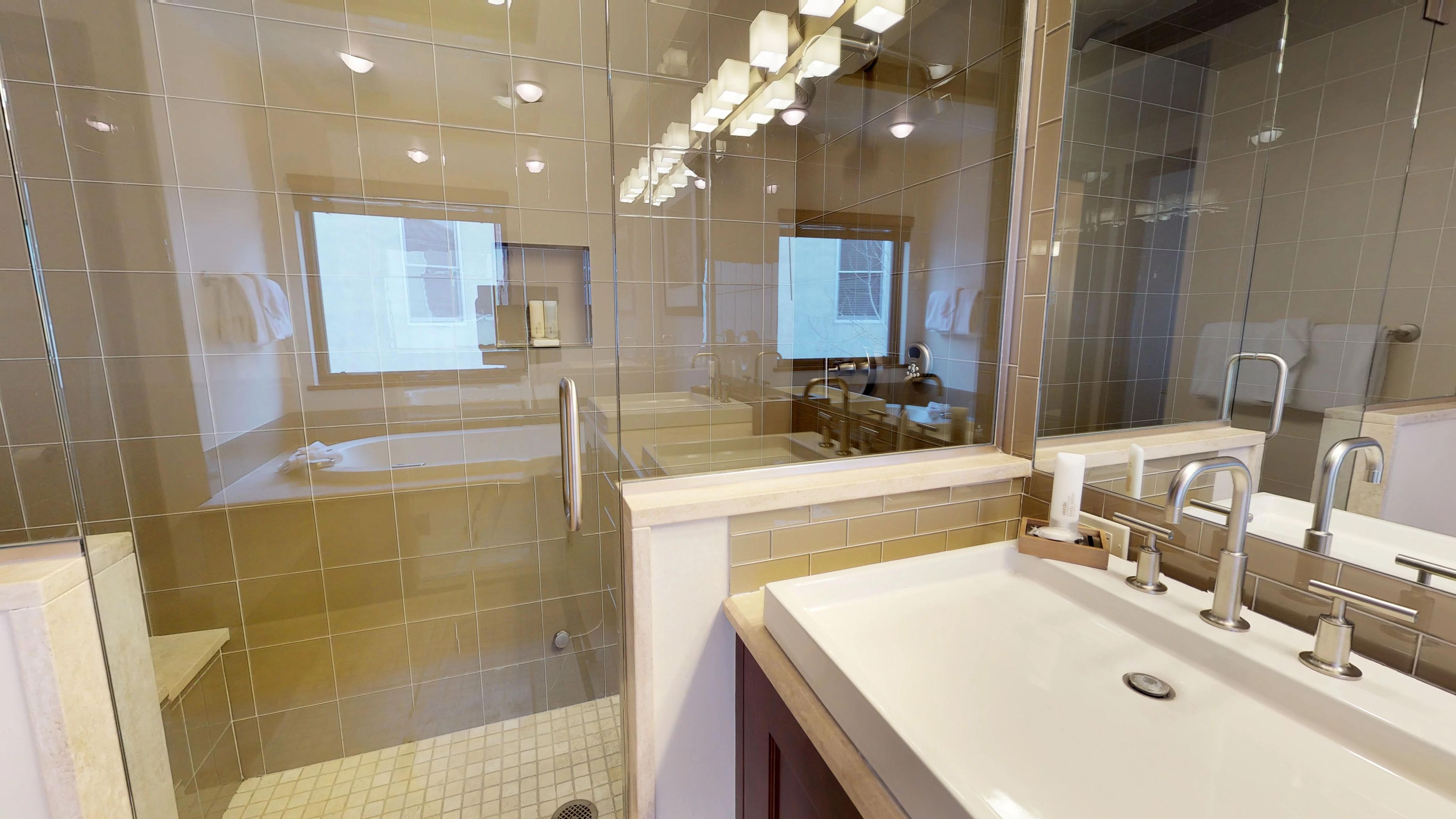 A modern bathroom with a large mirror, a sink with a vanity, and a shower area.