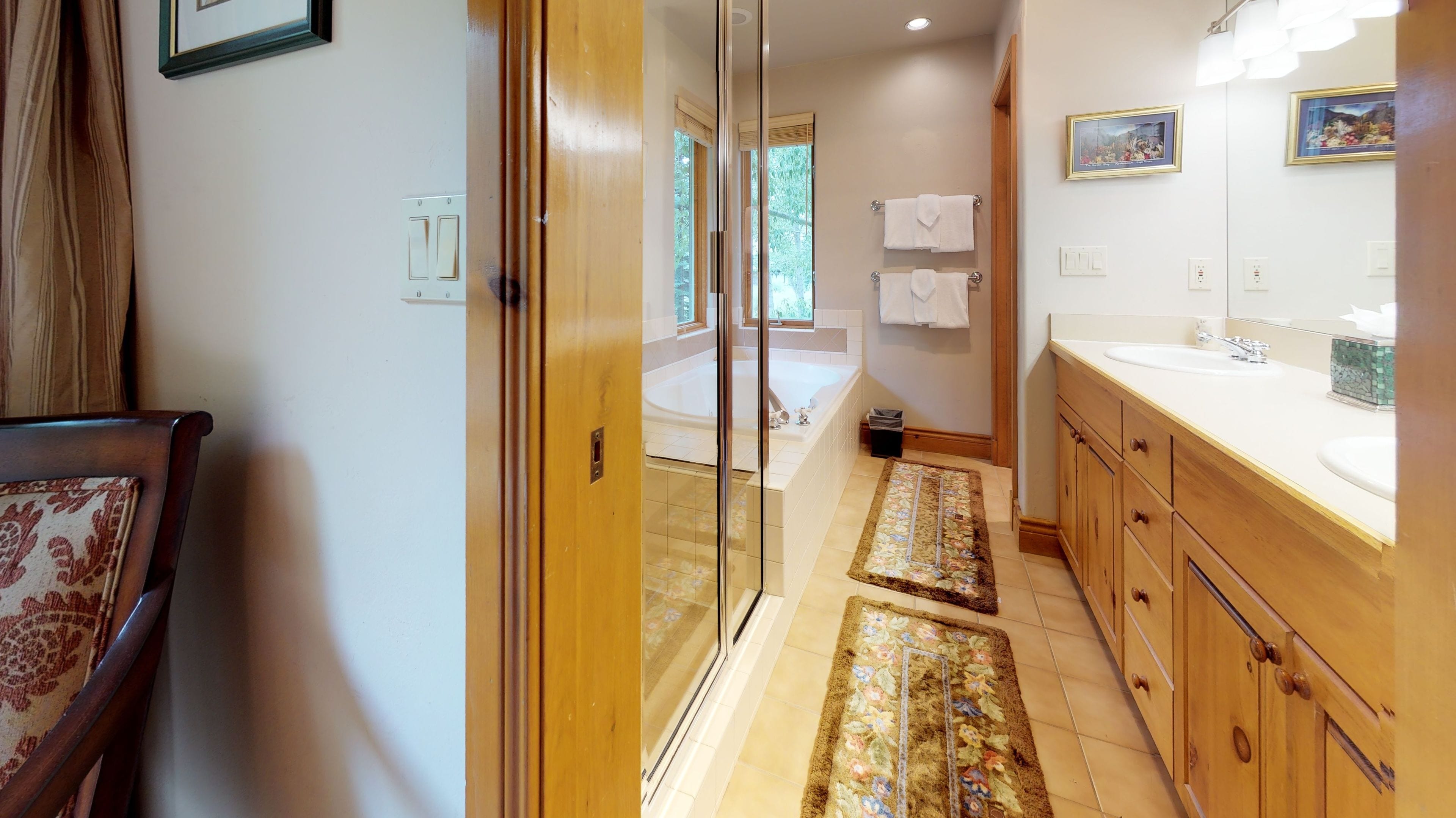 Un baño moderno con cabina de ducha de vidrio, una bañera y armarios de madera.