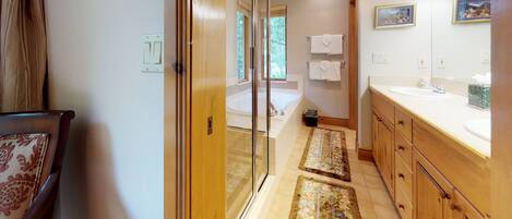 Un baño moderno con cabina de ducha de vidrio, una bañera y armarios de madera.
