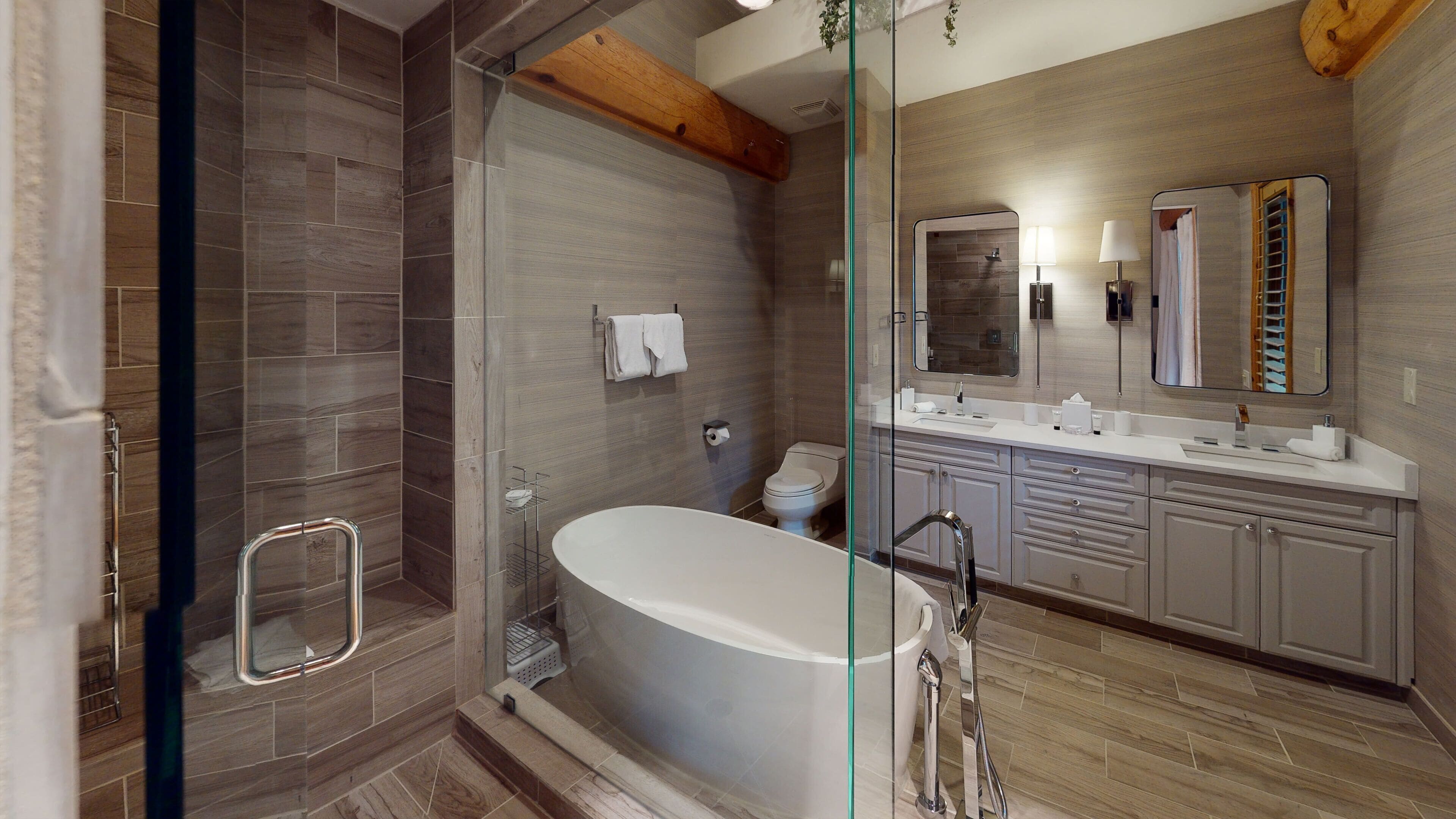 A modern bathroom with a glass-enclosed shower, a freestanding bathtub, and a vanity with a large mirror.