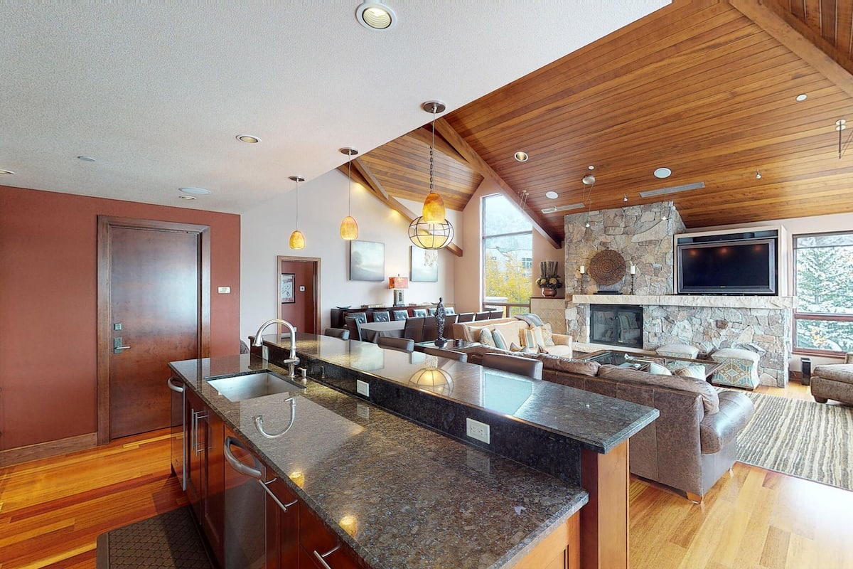 A spacious kitchen with granite countertops, a large island, and a dining area with a stone fireplace.