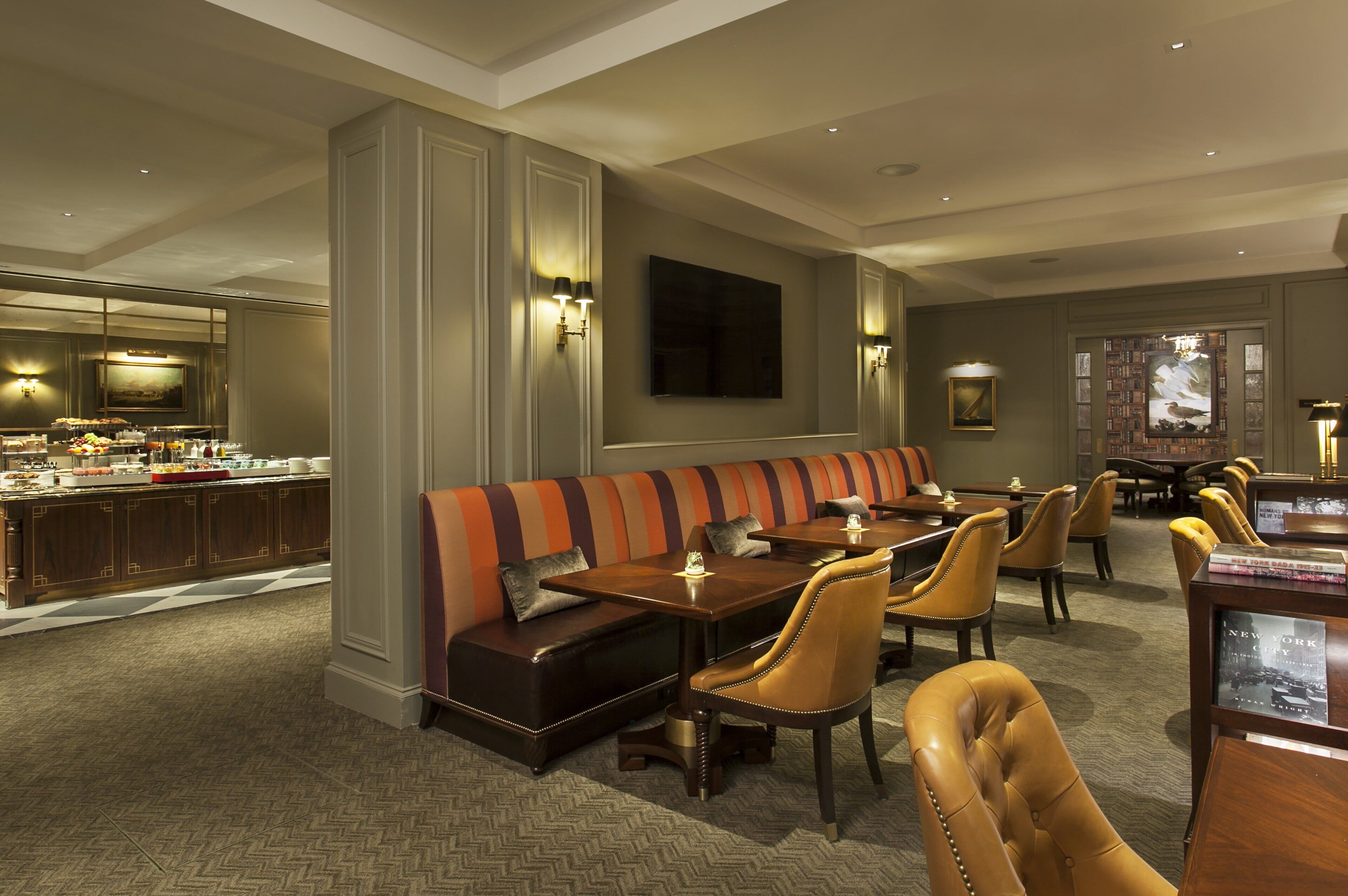 A hotel dining area with a long bench, multiple tables, and chairs.