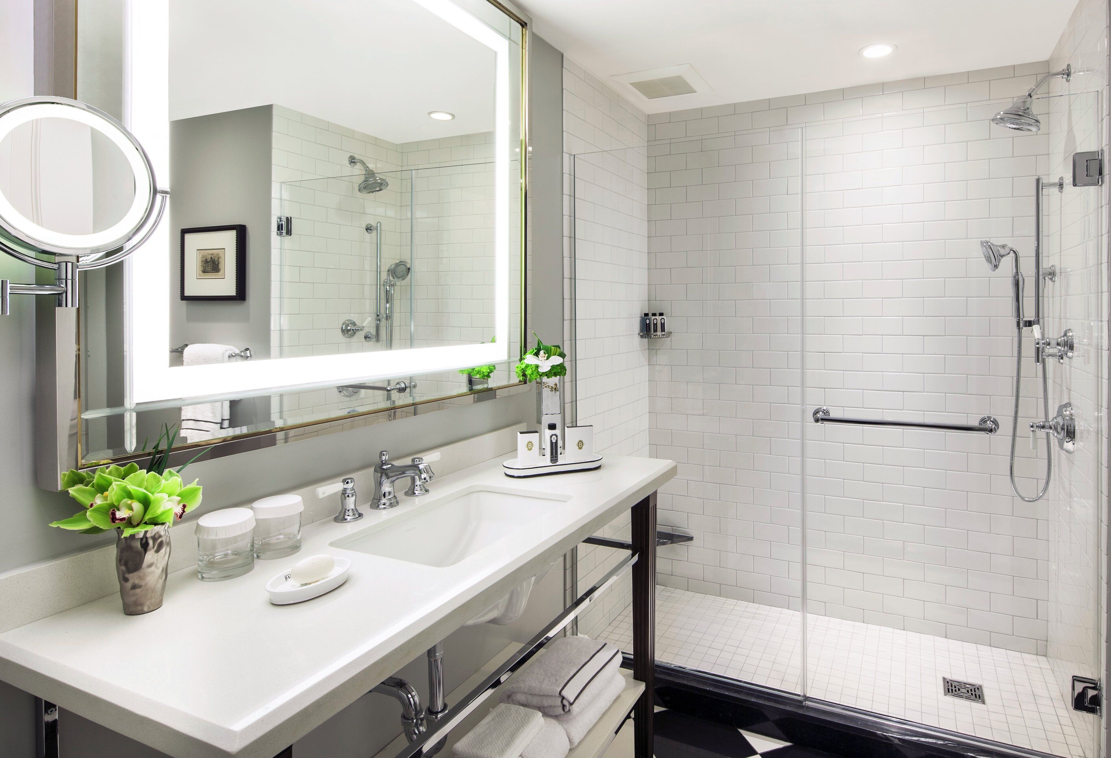Un baño moderno con un espejo grande, dos lavamanos, zona de ducha y un perchero para toallas.