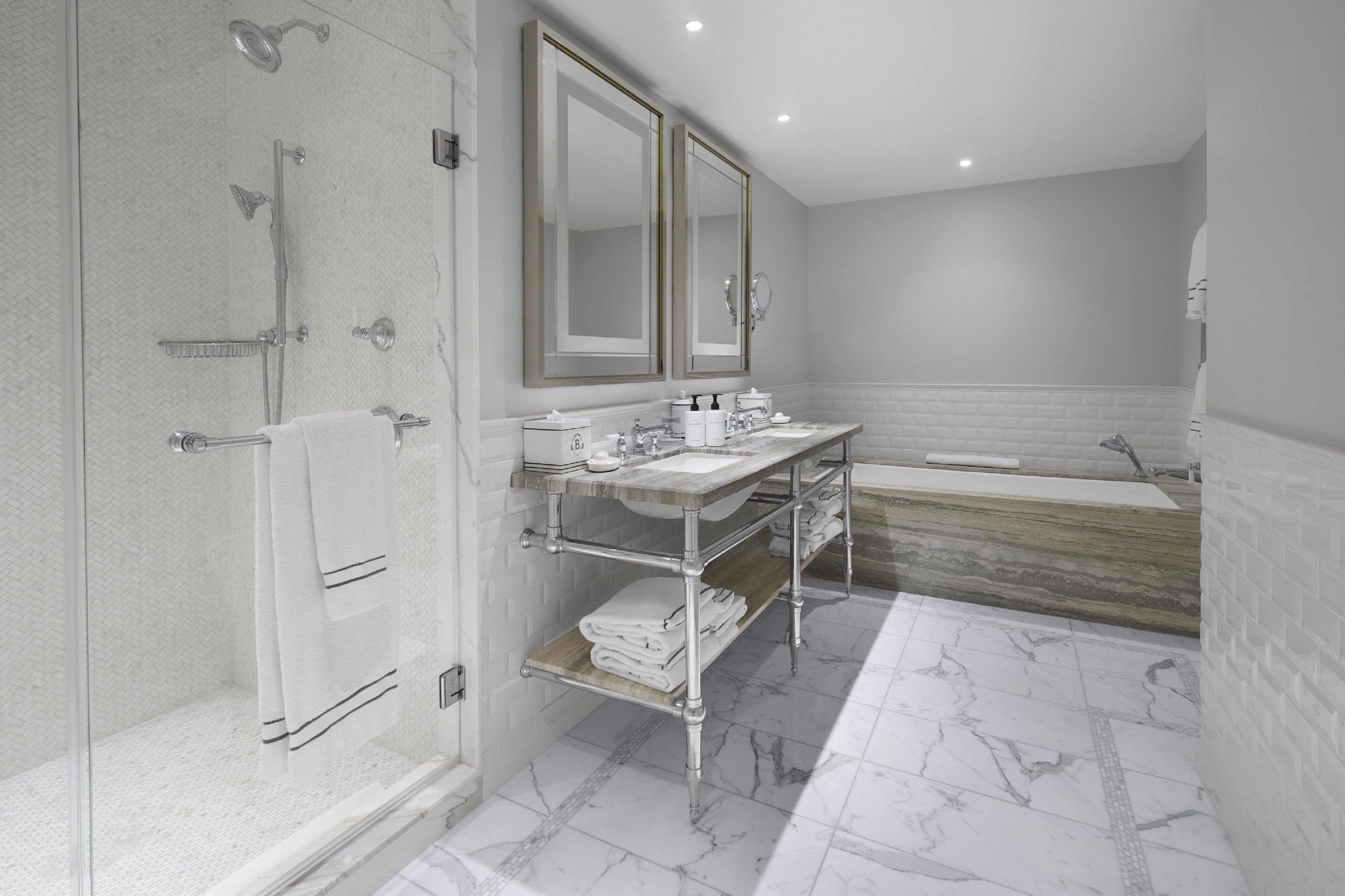 Een moderne badkamer met een inloopdouche, dubbele wastafels en een grote spiegel.