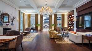 A spacious living room with a grand chandelier, a fireplace, and a large television. - InterContinental New York Barclay by IHG (New York)