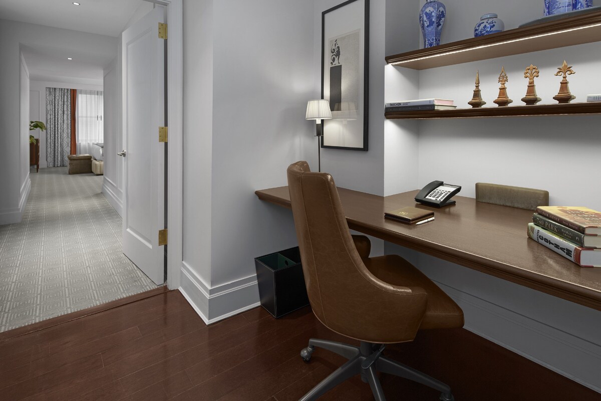 A modern office space with a desk, chair, and shelves with decorative items.