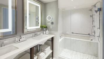 A modern bathroom with two sinks, a large mirror, a shower with a glass door, and a marble floor.