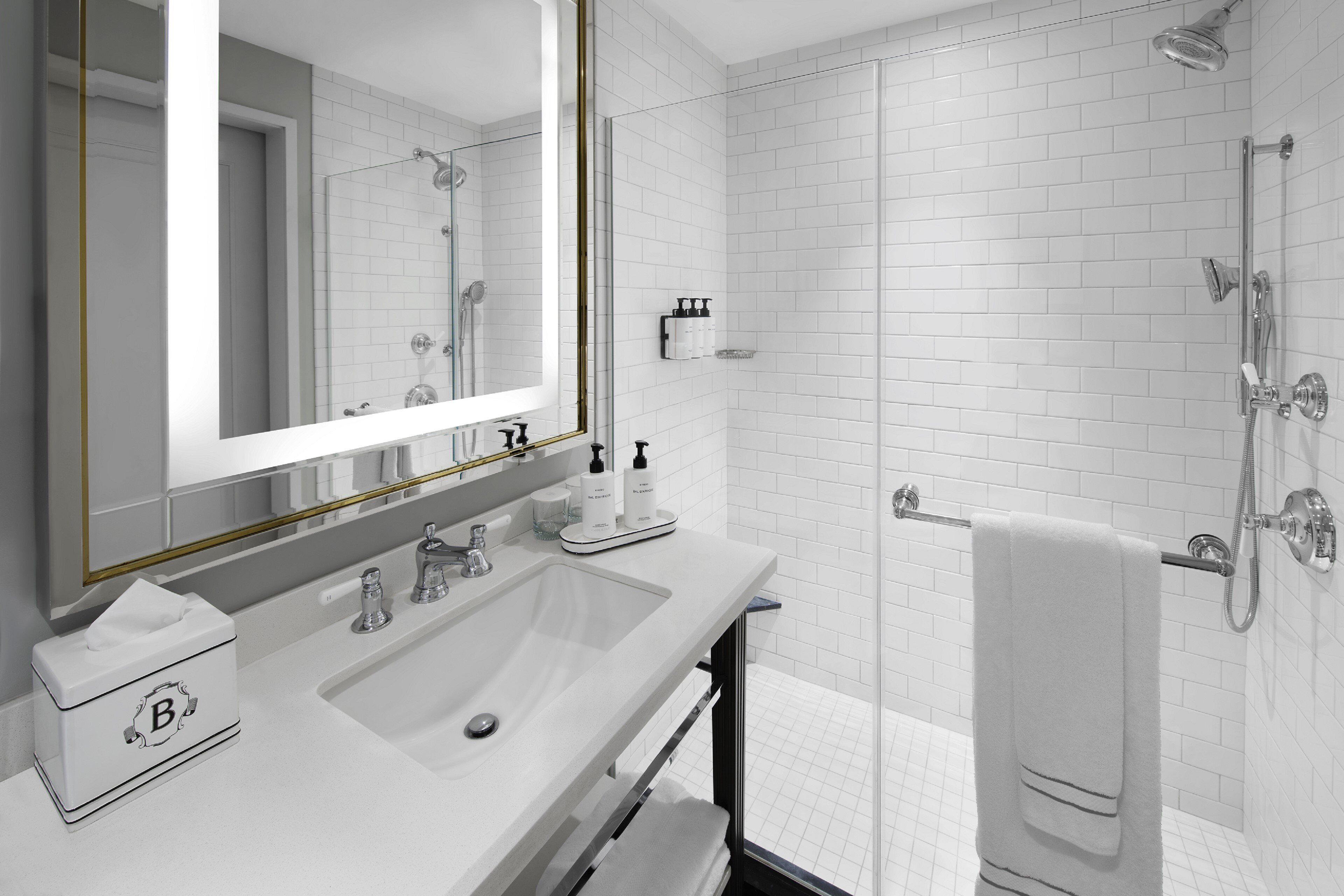 A modern bathroom with a large mirror, white sink, and a glass-enclosed shower.