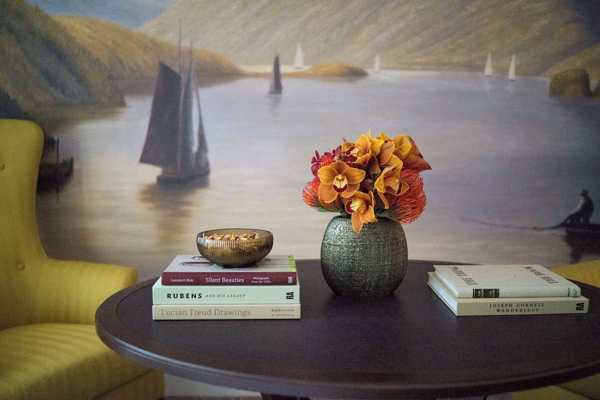 A round table with a vase of flowers, a bowl, and books.