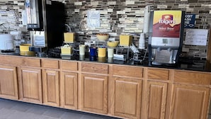 A coffee station with a Folgers coffee maker, a coffee dispenser, and various cups and containers. - Days Inn by Wyndham Staunton (Staunton)