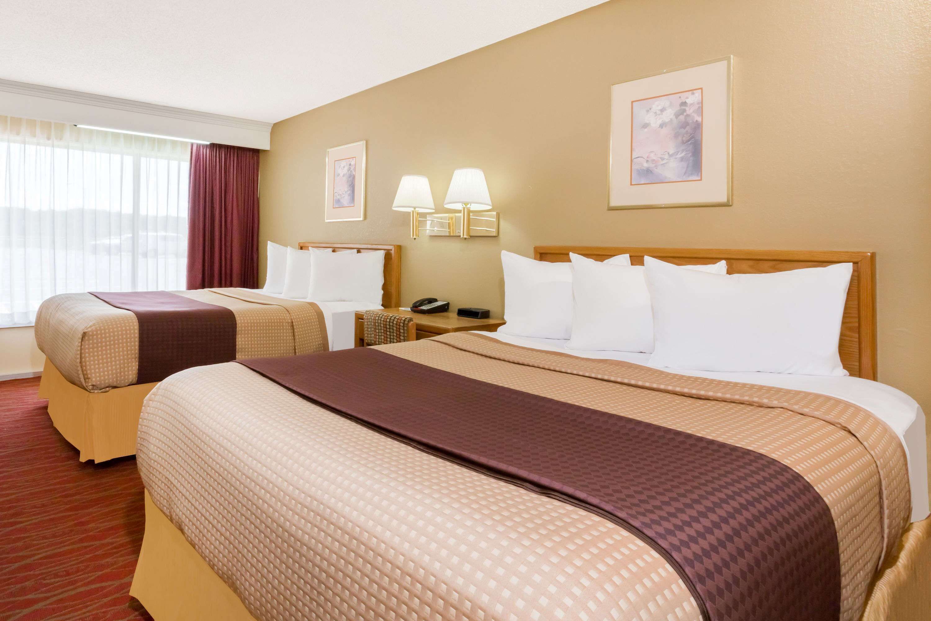 Habitación de hotel con dos camas, un escritorio, una silla, un teléfono y dos lámparas de pared.