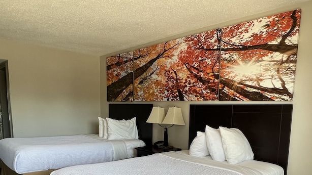 A hotel room with two single beds and a larger bed, all with white bedding. - Days Inn by Wyndham Staunton (Staunton)