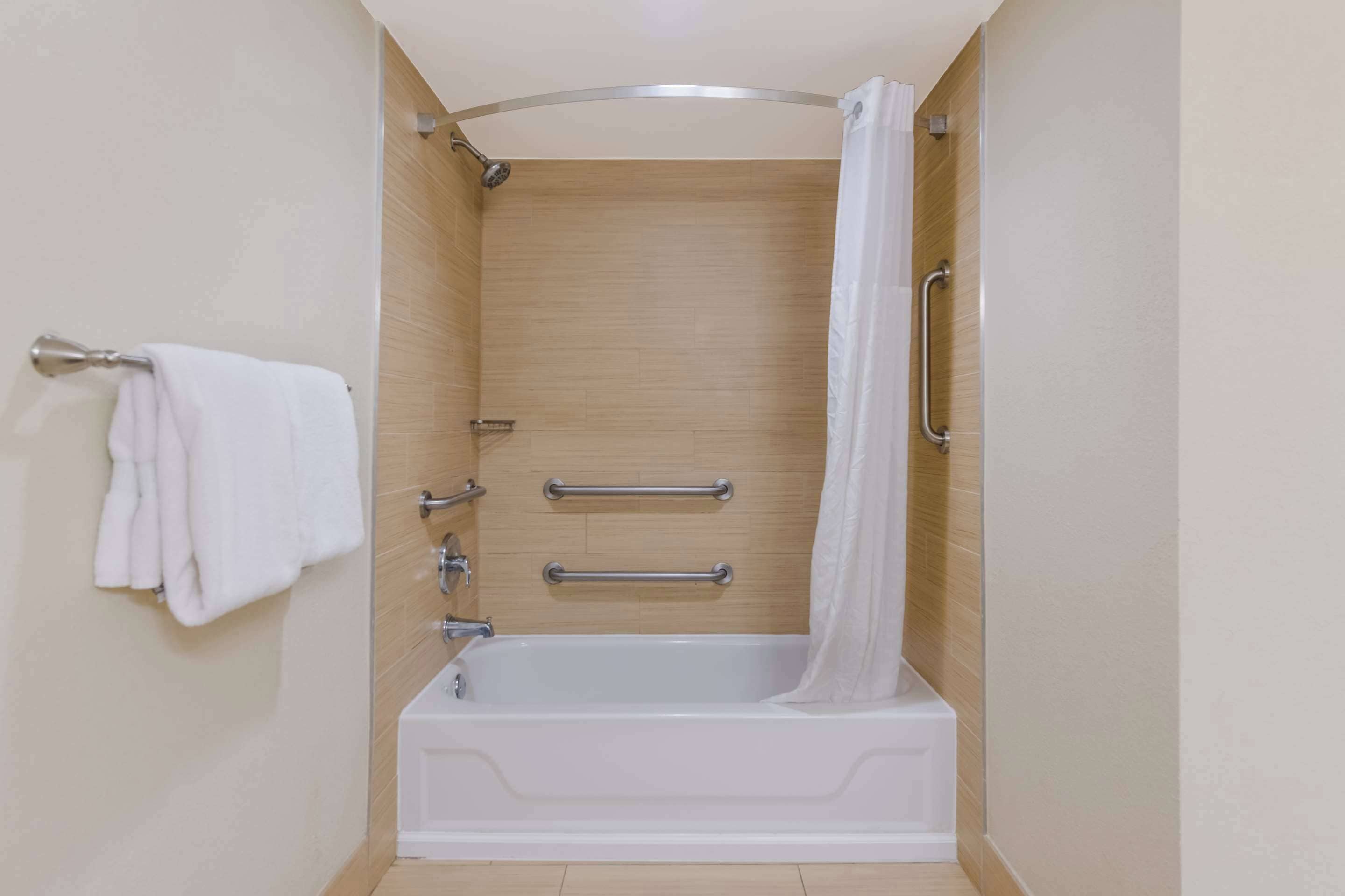 Un baño moderno con bañera, barras de apoyo y toallero.