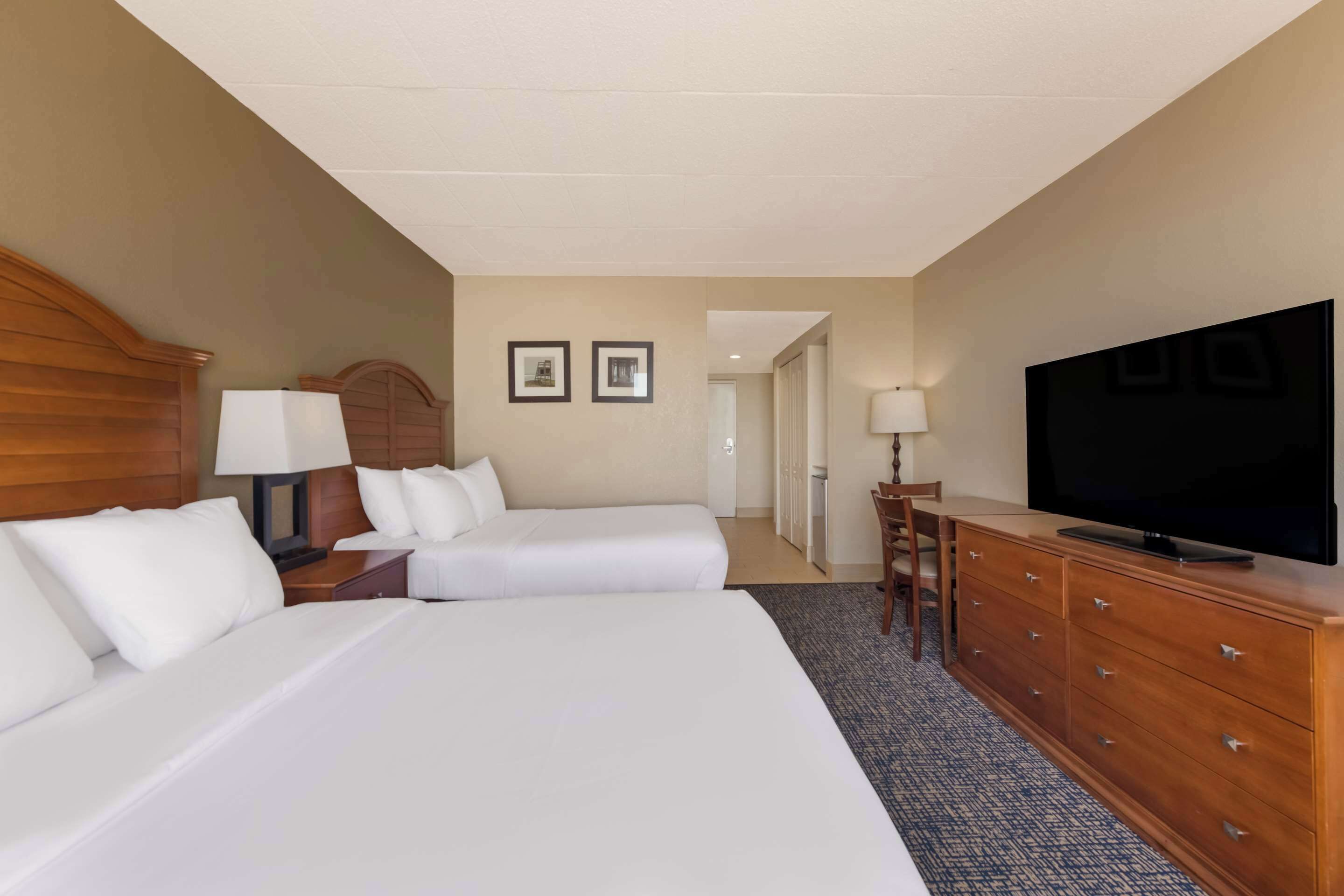 A hotel room with two beds, a TV, a desk, and a chair.