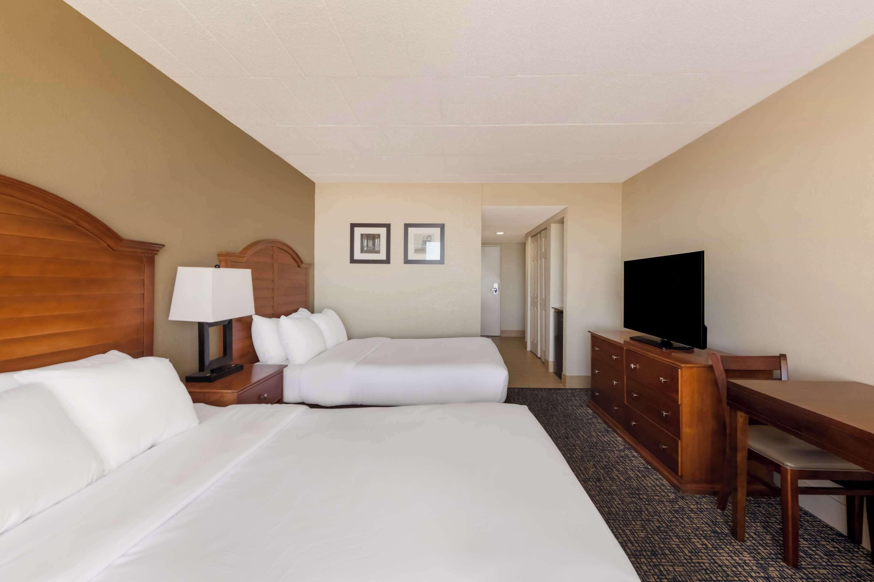 A hotel room with two beds, a TV, a desk, and a dresser.