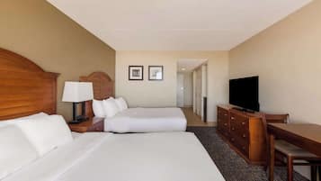 A hotel room with two beds, a TV, a desk, and a dresser.