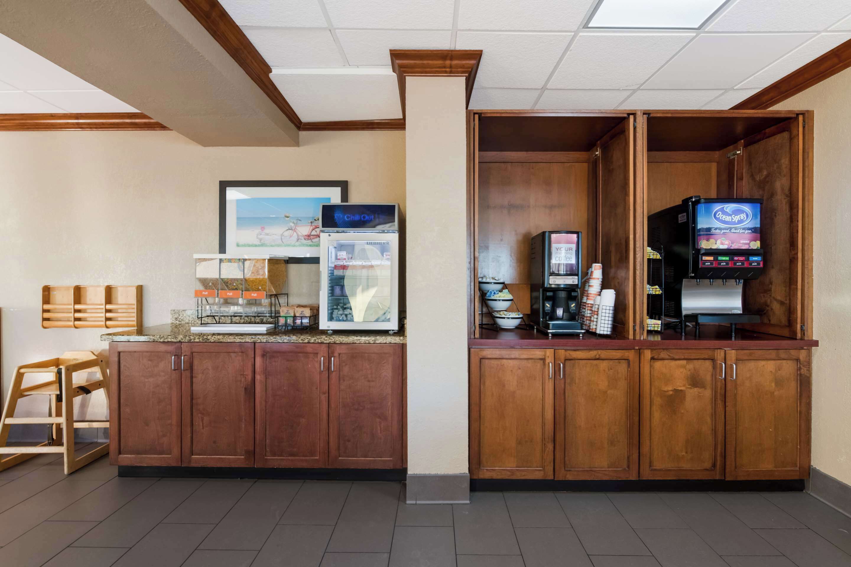 A hotel lobby with a reception desk, a coffee machine, a refrigerator, and a vending machine.