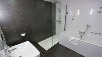 A modern bathroom with a white sink, a glass-enclosed shower, and a white bathtub.