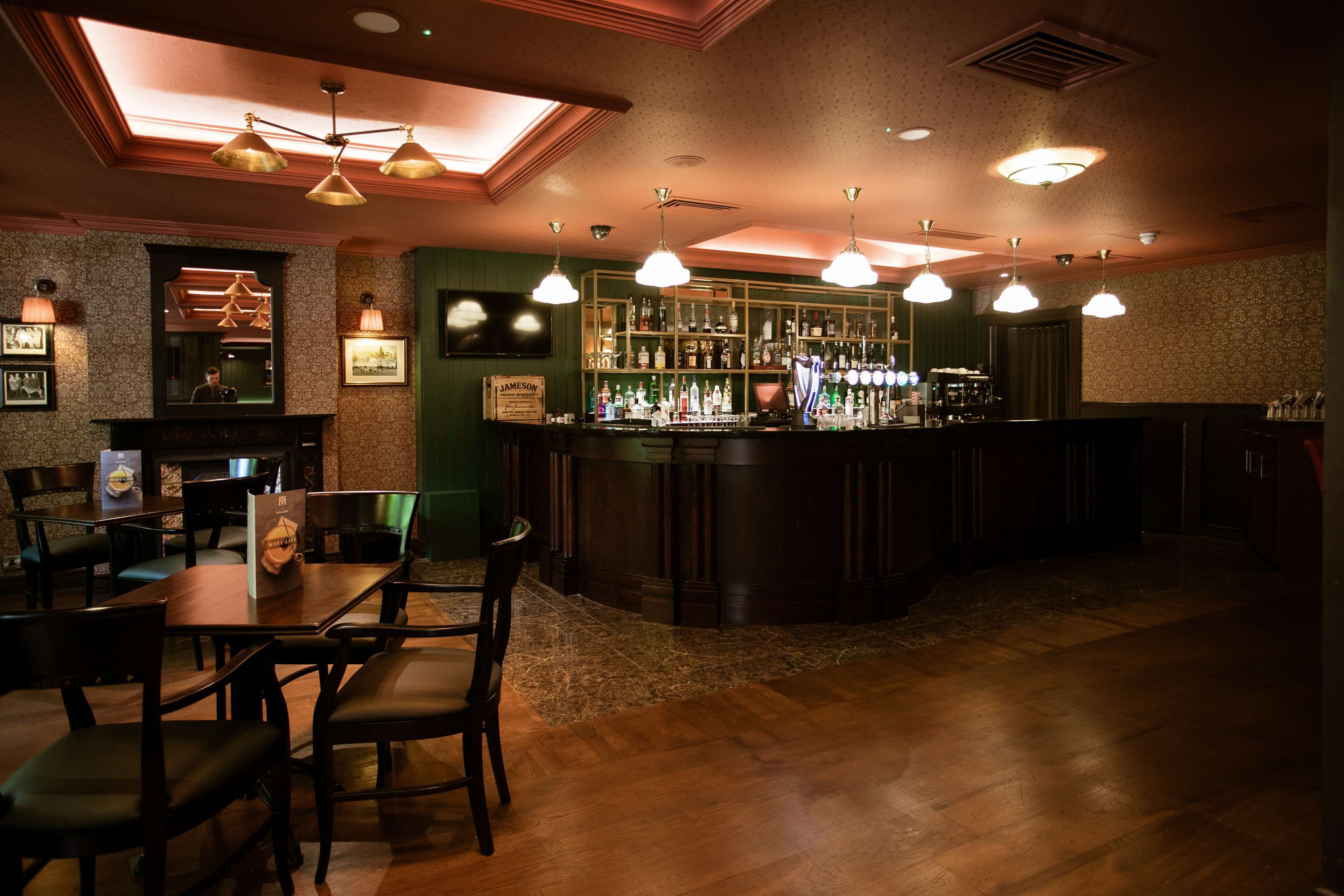 A bar area with wooden furniture, a bar counter, and hanging lights.