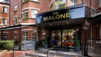 A brick building with a black awning labeled "The Malone."