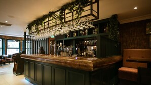 A bar area with a counter, shelves with bottles, and hanging glasses. - The Malone Hotel (Belfast)