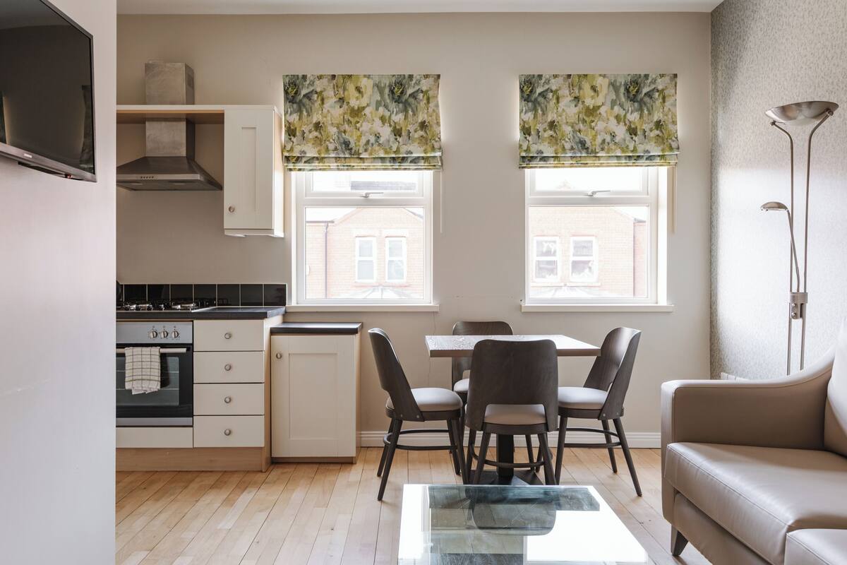 A modern kitchen with a dining area, a sofa, and a TV.