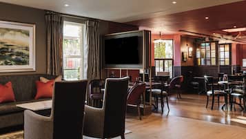 A hotel lobby with a sofa, chairs, a television, and a bar area.