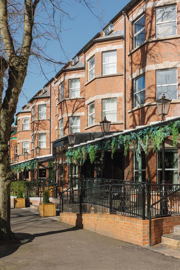 A brick building with multiple windows, a black iron railing, and a tree in the foreground. - The Malone Hotel (Belfast)