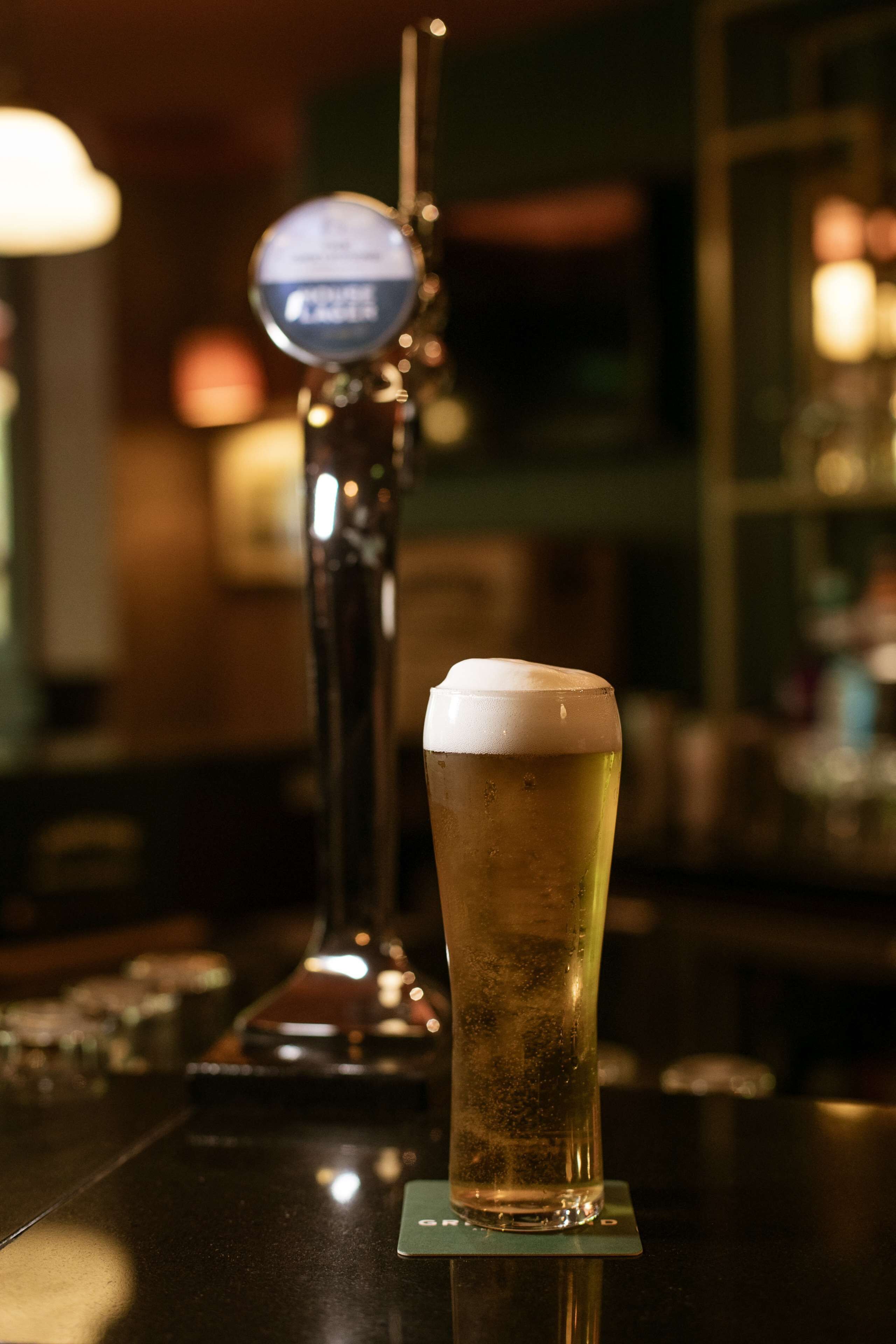 Une tireuse à bière et un verre de bière sur le comptoir d’un bar.