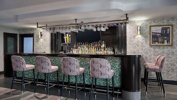 A bar area with a counter, bar stools, and a variety of bottles.