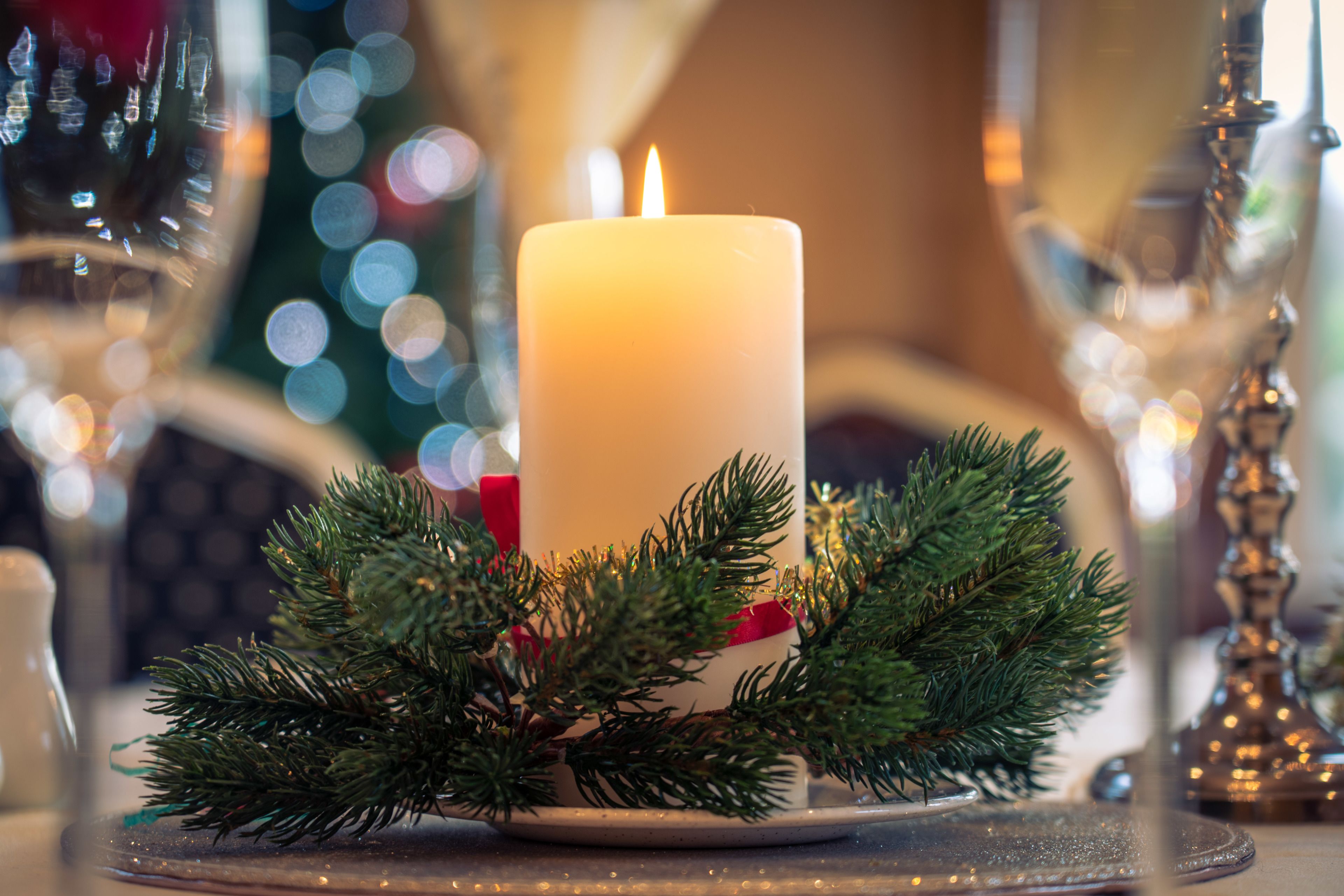 A candle on a table with a plate and greenery.