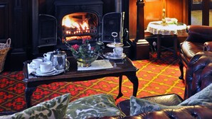 A cozy room with a fireplace, leather furniture, and mounted deer heads. - Ledgowan Lodge Hotel (Achnasheen)
