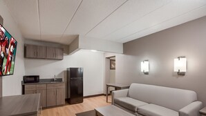 Ein modernes Wohnzimmer mit einer Couch, einem Esstisch und einer Küchenzeile mit Schränken und Geräten.