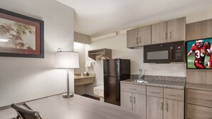 Eine moderne Küche mit Kühlschrank, Mikrowelle und einer Arbeitsplatte aus Granit.