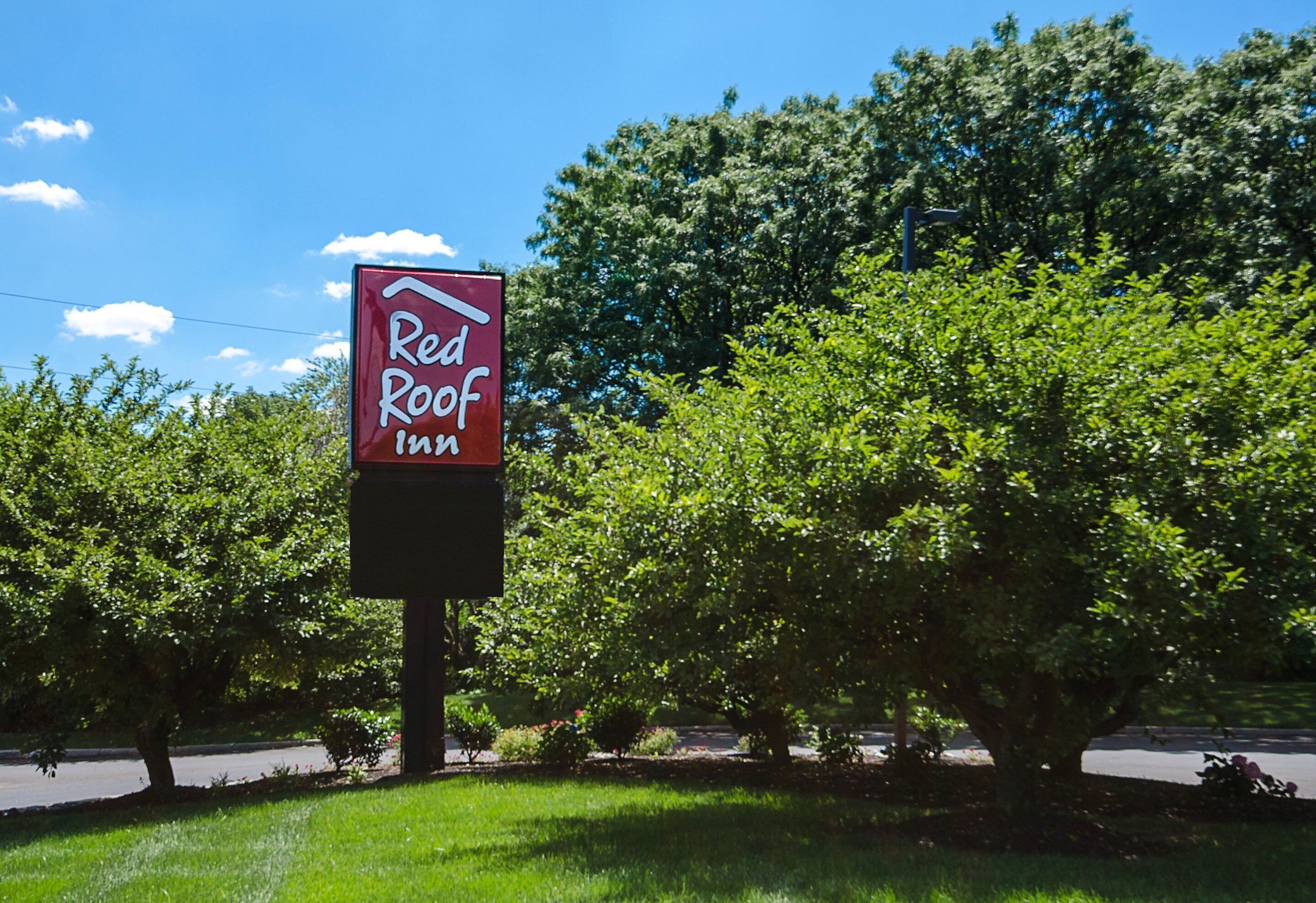 Placa do Red Roof Inn com vista clara da vegetação ao redor.