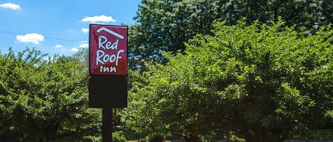A sign for Red Roof Inn with a clear view of the surrounding greenery.