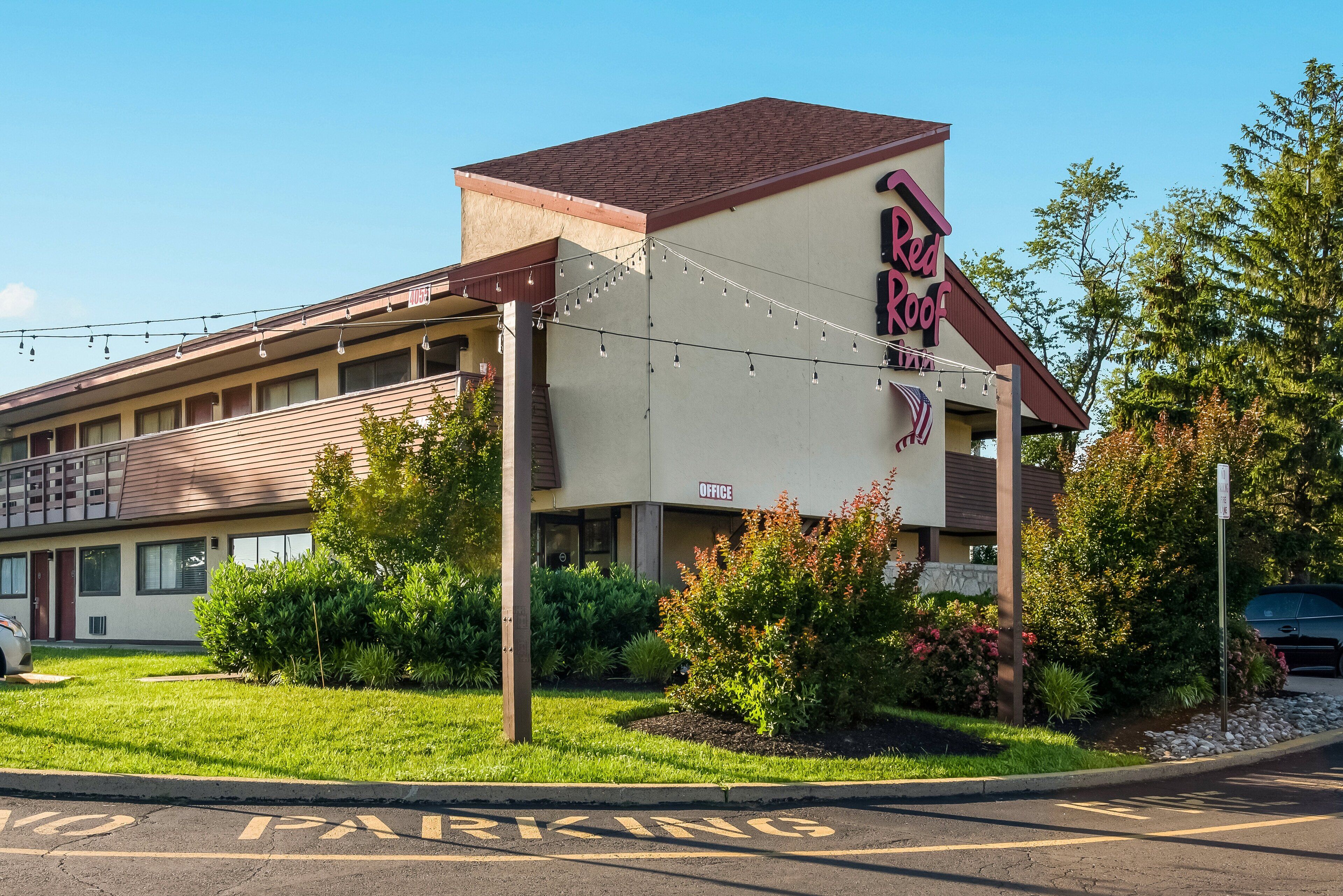 A motel with a sign reading "Red Roof Inn" and an office building adjacent to it.
