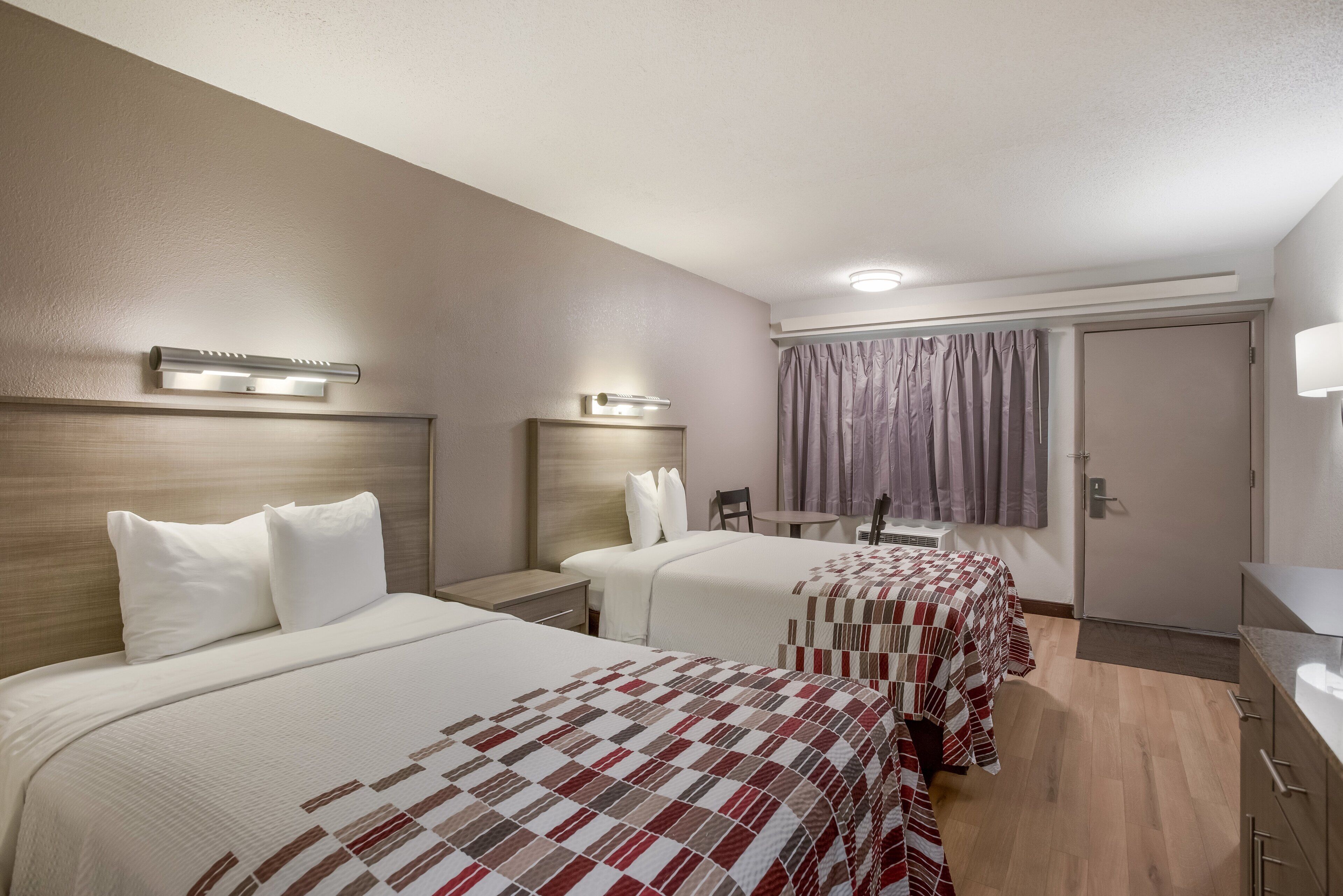 Una habitación de hotel con dos camas, una mesita y una silla.