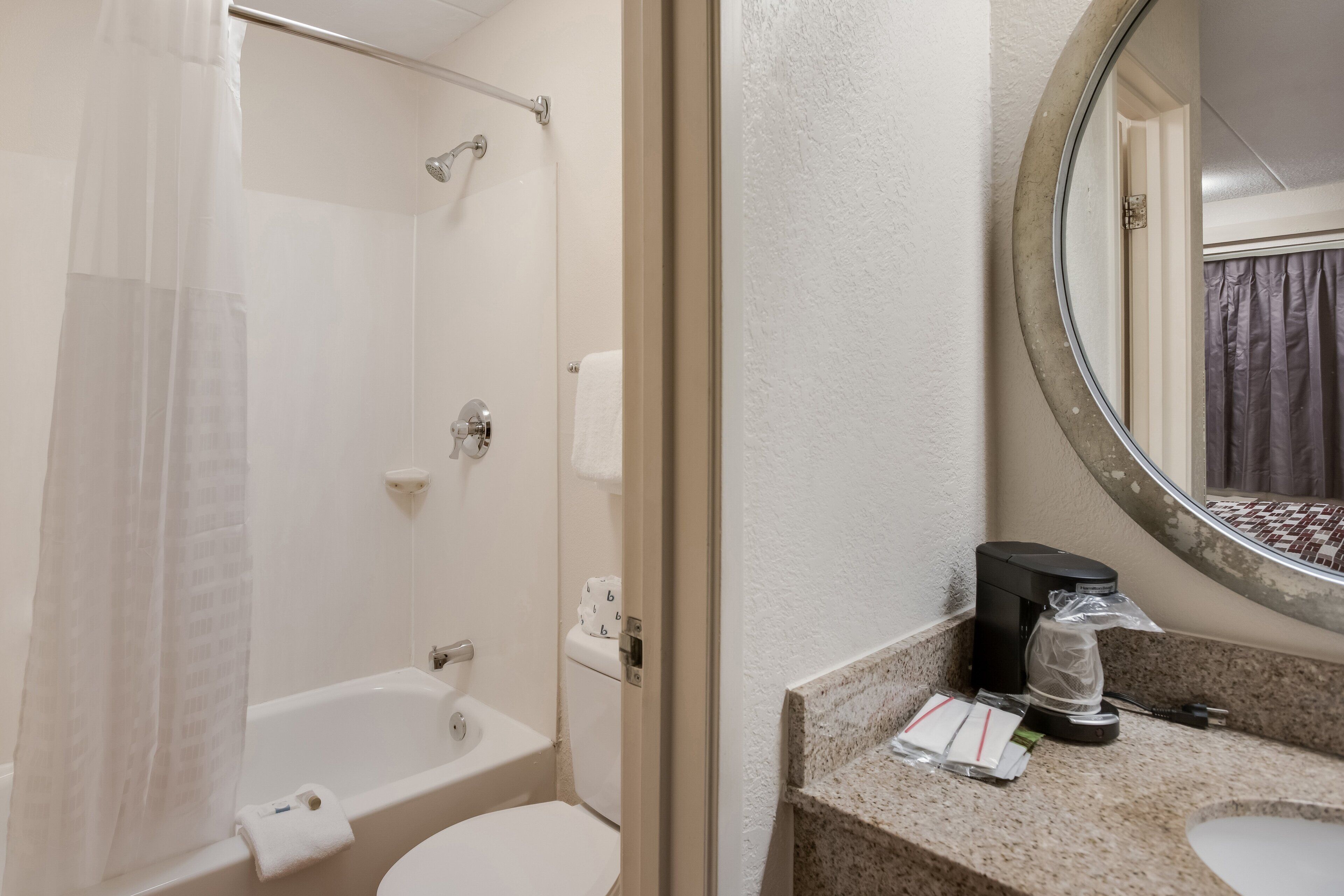 A bathroom with a bathtub, toilet, and a sink with a coffee maker.